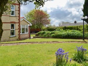 una casa con un patio con flores púrpuras en Cranford House, en Woolfardisworthy