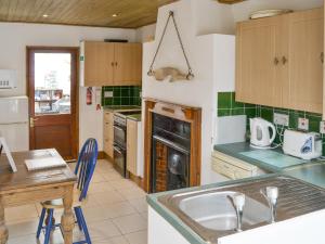 a kitchen with a sink and a stove top oven at Beach Cottage in Winterton-on-Sea