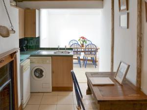 a kitchen with a table and a washing machine at Beach Cottage in Winterton-on-Sea