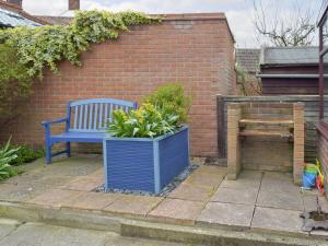 a blue bench sitting next to a brick wall at Beach Cottage in Winterton-on-Sea