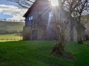 une vieille maison en pierre avec le soleil brillant sur elle dans l'établissement Magpie - Uk6546, à Llanfihangel-Bryn-Pabuan