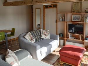 a living room with a couch and a tv at The Old Cow Shed in Wickwar