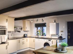 a large kitchen with white cabinets and a table at Chattox Cottage in Barrowford