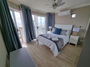 a bedroom with a bed with blue pillows and a window at Diaz Views 10 in Jeffreys Bay