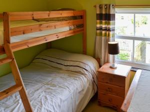 1 dormitorio con 2 literas y mesa con lámpara en Willow Cottage, en Newlyn East