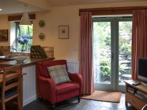 a living room with a red chair and a kitchen at Cil Y Felin in Beddgelert