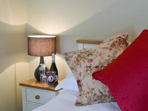 a bedroom with a bed with a red pillow and a lamp at The Coach House in South Brent