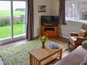 a living room with a television and a table with flowers at Rosemarys Sea View in Bacton