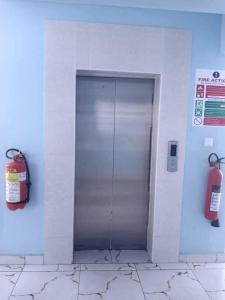 einem Metallaufzug in einem Gebäude mit einem Feuerlöscher in der Unterkunft 2 B/room Nyali City Mall W/Pool in Mombasa