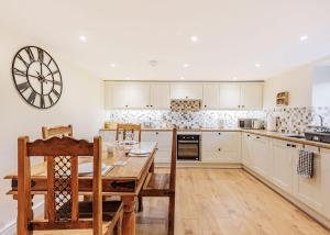 cocina con mesa y reloj en la pared en Sgubor Fach en Pen-y-bont-fawr