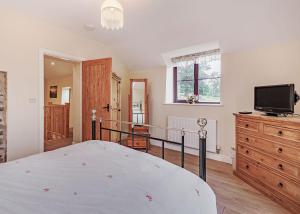 a bedroom with a bed and a tv on a dresser at Sgubor Fach in Pen-y-bont-fawr