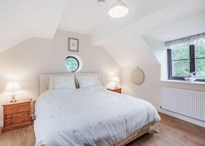 a white bedroom with a large bed and two windows at Sgubor Fach in Pen-y-bont-fawr