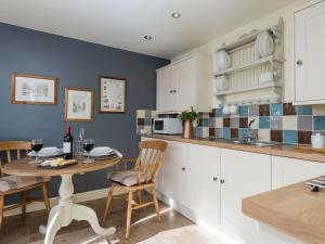 a kitchen with a table and chairs and a microwave at Cow Pasture Cottage in Hallington