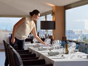 a woman is standing over a table in a restaurant at Hotel Saratoga in Palma de Mallorca