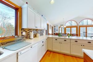a kitchen with white cabinets and a large window at Ski Bike the East in Stowe +84 photos