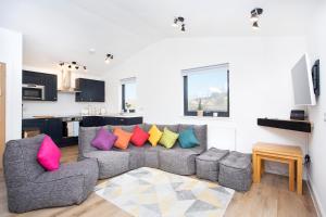 sala de estar con sofá gris y almohadas coloridas en Shiphorns luxury cabin with a hot tub en Eddleston