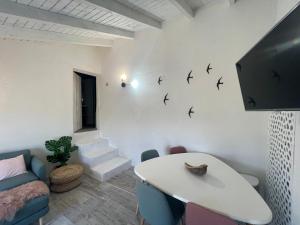 a living room with a white table and birds on the wall at Casa da Estrelinha in Carrapateira