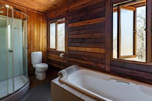 a bathroom with a bath tub and a toilet andwindows at Palala River Cottages in Vaalwater +43 photos