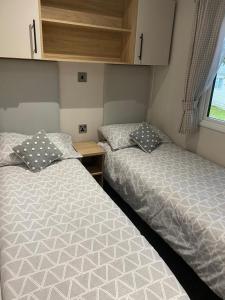 two twin beds in a small room with a window at Coghurst Hall Holiday Home Sleeps 6, 2 bedrooms in Hastings