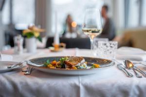 einen Teller mit Essen auf einem Tisch mit einem Glas Wein in der Unterkunft Naturhotel Tandler in Sankt Jakob in Defereggen