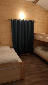 Cette chambre comprend 2 lits et un rideau noir. dans l'établissement La tanière du lac d Aiguebelette, à Lépin-le-Lac