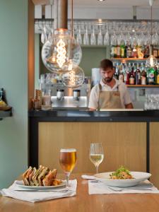 a man behind a counter with two plates of food and wine at Hotel Saratoga in Palma de Mallorca