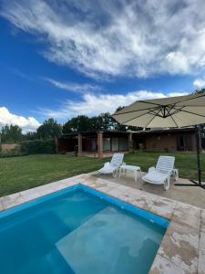 a pool with two chairs and an umbrella at Pergolas Guest House - Pileta, Vinos y Montaña in Vista Flores
