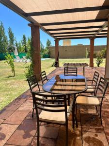 un patio con mesa y sillas bajo una pérgola en Pergolas Guest House - Pileta, Vinos y Montaña en Vista Flores