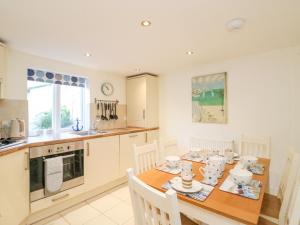 une cuisine avec une table en bois et des chaises ainsi qu'une salle à manger dans l'établissement Lobster Cottage, à Weymouth