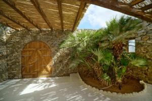 a stone building with a wooden door and palm trees at Zinas Villas in Fanari