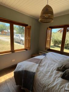 1 dormitorio con 1 cama y ventanas con un coche al aire libre en Casa Rincon Radales en San Martín de los Andes