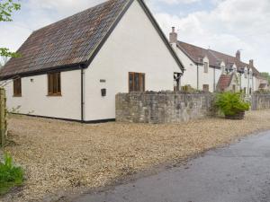 a white house with a stone wall next to a building at The Lodge in Wedmore