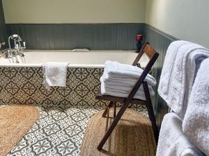 baño con bañera y silla con toallas en Creag Darach Cottage, en Aberfoyle