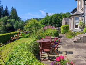 un patio con mesa y sillas en un jardín en Creag Darach Cottage, en Aberfoyle