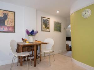 uma sala de jantar com uma mesa de madeira e cadeiras brancas em Cottage On The Green em Calne