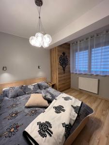 a bedroom with a large bed and a chandelier at Apartament Wilcza Jama z kominkiem - Viva pod Giewontem Apartamenty in Zakopane