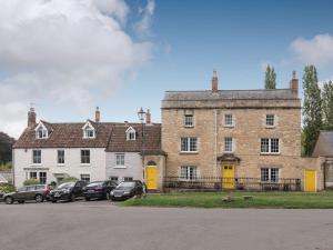 a large brick building with cars parked in a parking lot at Cottage On The Green in Calne