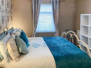 a bedroom with a bed with blue pillows and a window at Jasmins Retreat in Cleveleys