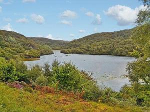 a river in the middle of a valley with mountains at Canisp View in Achmelvich