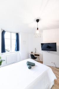 biała sypialnia z łóżkiem i telewizorem w obiekcie Le Greco w mieście Saint-Étienne