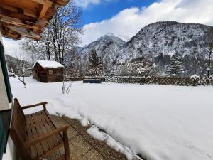 un patio cubierto de nieve con un banco y una montaña en Ferienwohnung Drexel, en Steeg