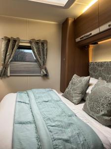a bedroom with a bed and a window at Self Contained Holiday Home Caravan in Corsham