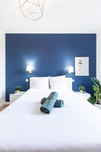 niebieska sypialnia z białym łóżkiem z 2 poduszkami w obiekcie Le Greco w mieście Saint-Étienne