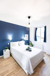 sypialnia z dużym białym łóżkiem z niebieską ścianą w obiekcie Le Greco w mieście Saint-Étienne