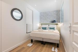 a bedroom with a bed with a mirror and slippers at Sweet Inn - Pont Neuf in Paris