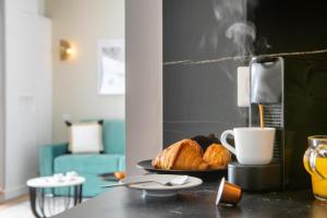 einen Tisch mit einem Teller Croissants und einer Tasse Kaffee in der Unterkunft Sweet Inn - Pont Neuf in Paris