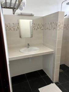 a white bathroom with a sink and a mirror at Maison T3 neuve fonctionnelle in Matoury