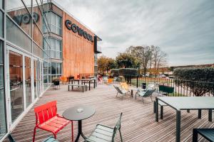 una terraza de madera con sillas y mesas y un edificio en COWOOL Cergy, en Cergy