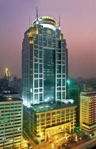 ein hohes Gebäude mit einer Uhr darüber in der Unterkunft Asia International Hotel Guangdong in Guangzhou