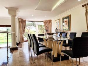 una sala da pranzo con tavolo e sedie nere di Spacious Golf & Wildlife Estate in Hartbeespoort 10 sleeper a Hartbeespoort